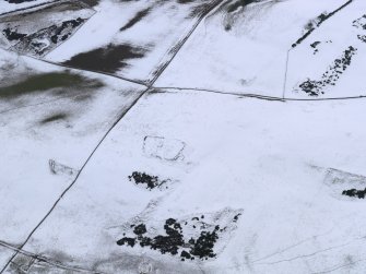 Oblique aerial view of the snow-covered remains of the settlement at Mire Loch, taken from the NNE.