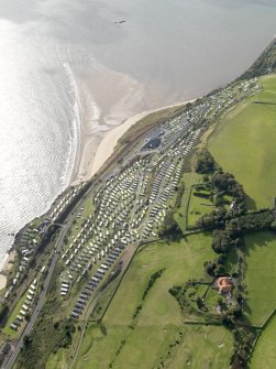 Oblique aerial view centred on the Pettycur Bay caravan park with Kinghorn golf course and the remains of the anti-aircraft battery adjacent, taken from the NE.