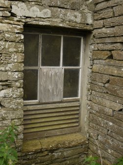 Detail or original window at ground level showing louvered section to allow ventilation.