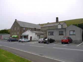 View of the gasworks from John Street showing the retort house behind. The white, single-storey building was the original coal store. To the left of this was the gasworks manager's house.