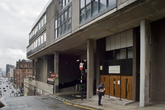 View of street level entrance to Bourdon Building, showing timber entrance doors to main libray to left and recessed entrance to studios on opposite side of the bridged road.