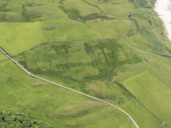 Oblique aerial view centred on the remains of the earthwork enclosures and the rig, taken from the NNE.