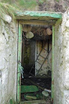 Detail. View of the entrance doorway within the central bay of the East elevation of the traditional cottage at 4 Balevullin. Stones can be seen hanging across the door opening - these were attached by rope (laterly to wire netting) and used as weights to hold the thatching down. Originally they would have sat above the level of the wallhead.