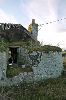View of the third bay of the East elevation of the traditional thatched cottage at 4 Balevullin, taken from the East. The thickness and curved form of the external wall to the North of the cottage can be appreciated in this photograph, as can the outward tilt of the chimney stack.