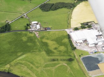 Oblique aerial view of the cropmarks of the barrow and possible field boundary with Priestdykes farmstead beyond, taken from the E.