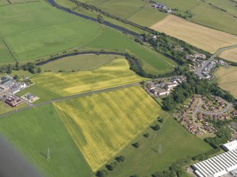 General oblique aerial view of the cropmarks of the cursus monument and pits with Drybridge village adjacent, taken from the W.