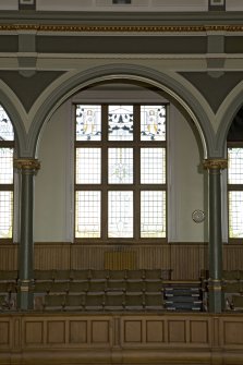 Interior. Main hall.  Detail of east balcony showing arch and columns.