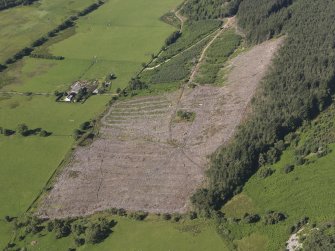 Oblique aerial view of Inchindown oil storage site, showing buildings on the surface, filter beds, square water reservoir and a trackway running from middle to top of photograph which ran between the two tunnel portals and to the spoil heap at the top of the image, taken from the ENE.