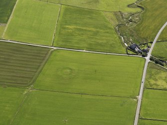 Oblique aerial view of the Hall of Ireland with a vegetation mark showing the ditch and the Mill of Ireland adjacent, taken from the WNW.