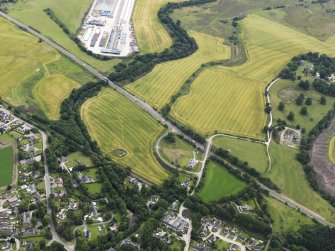 Oblique aerial view of the cropmarks of the enclosure with the bridges adjacent, looking E.