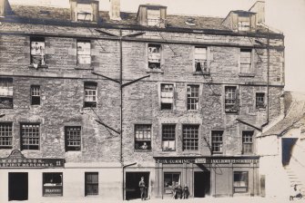 View of buildings at Abbey Strand, Edinburgh showing Woodcock Spirit Merchant and A Cumming Holyrood Restaurant.
Titled: "Abbey Sanctuary foot of Canongate. August 1903" 
