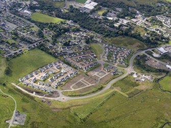 Oblique aerial view of the housing development on the N side of Portree on the site of the former farmsteads, looking SW.