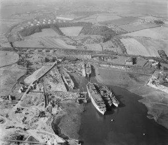 Thomas Ward and Sons Shipbreaking Yard, Inverkeithing.  Oblique aerial photograph taken facing west.  The vessels include a mine damaged large bulk carrier, a small bulk carrier, two large passenger liners and a general cargo ship.