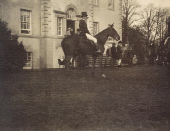 View of woman on horseback outside Duchal House.

