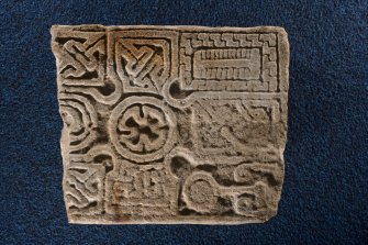View of fragment of cross slab, Drainie no 32, displaying mirror, comb and torc Pictish symbols
