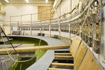 Interior. Curved wave tank building. View of modular work platforms, signal processing receivers (right). The platforms have been partially lifted to show how access to wavemakers achieved.