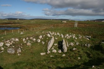 View of chamber and passage from SSW, with standing stone to NE of cairn.