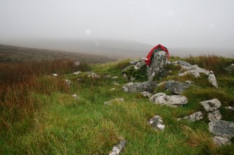 View from W of the only upright slab visible within the cairn.