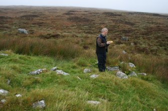 Mr Stratford Halliday, RCAHMS, recording the cairn and enclosure.