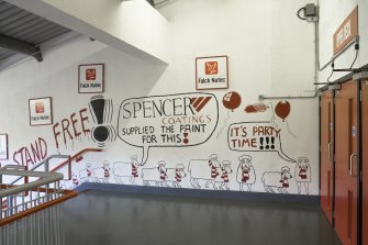 Interior. View of landing on main supporters' staircase within Richard Donald stand, showing graffiti by local cartoonist.