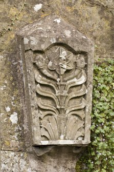 Detail of carved stone fragment set into wall adjacent to gate in garden to south of house.