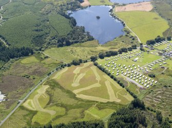 General oblique aerial view of the crannog in Loch Heron with the camp site in the foreground, taken from the NNE.