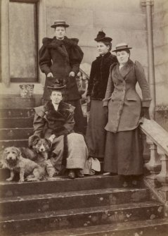 View of group of four ladies with two dogs probably at St Fort House.
