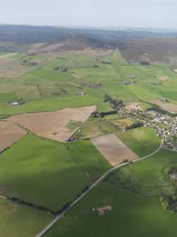 General oblique aerial view looking across the excavation of the enclosures at Barflat, with Rhynie village and Tap O'Noth beyond, taken from the SSE.