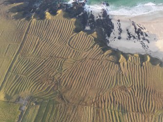 Oblique aerial view of the remains of the lazy beds, enclosures and head dyke at Carnan Thangadeir, taken from the SSE.