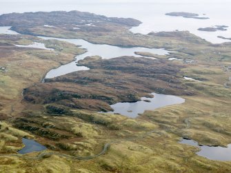 General oblique aerial view of the remains of  Dun Loch an Duna, the townships of Grimshader and Ceann Hurnavay, with associated mill and head dyke, Isle of Lewis, taken from the NW.