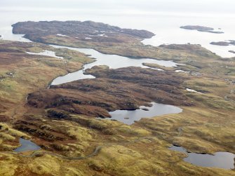 General oblique aerial view of the remains of  Dun Loch an Duna, the townships of Grimshader and Ceann Hurnavay, with associated mill and head dyke, Isle of Lewis, taken from the NW.