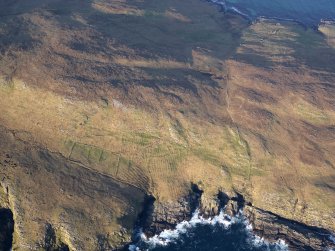 Oblique aerial view of the remains of a field system, field boundaries, and lazy beds at Mullach A' Lusgan, looking towards the remains of the township at The Aird, Berneray, taken from the S.