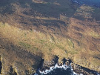 Oblique aerial view of the remains of a field system, field boundaries, and lazy beds at Mullach A' Lusgan, looking towards the remains of the township at The Aird, Berneray, taken from the S.