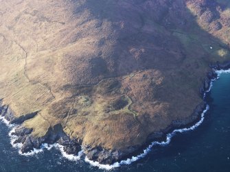 Oblique aerial view of the remains of the buildings, head dyke, field system, enclosures and lazy beds at Hecla Point, Mingulay, taken from the E.