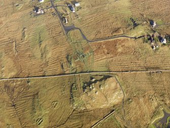 Oblique aerial view centred on the stone circle and stone row, the remains of the buildings and lazy beds at Calanais, taken from the SW.