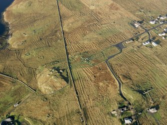 Oblique aerial view centred on the stone circle and stone row, the remains of the buildings and lazy beds at Calanais, taken from the SE.