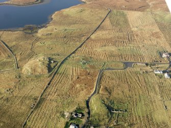 Oblique aerial view centred on the stone circle and stone row, the remains of the buildings and lazy beds at Calanais, taken from the E.