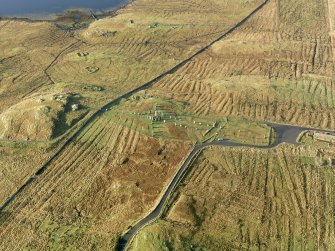 Oblique aerial view centred on the stone circle and stone row, the remains of the buildings and lazy beds at Calanais, taken from the ENE.