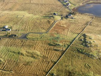 Oblique aerial view centred on the stone circle and stone row, the remains of the buildings and lazy beds at Calanais, taken from the W.