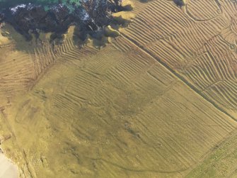 Oblique aerial view of the remains of the lazy beds, enclosures and head dyke at Carnan Thangadeir, taken from the S.