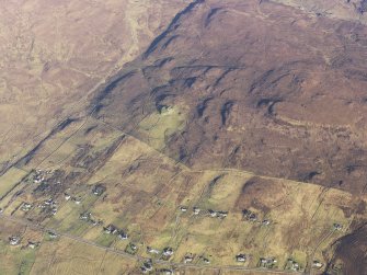 Oblique aerial view of the remains of the Dun Hallin broch and the township of Dunhallin, with the remains of the adjacent field system, enclosuires and lazy beds, Waternish, Skye, taken from the SW.