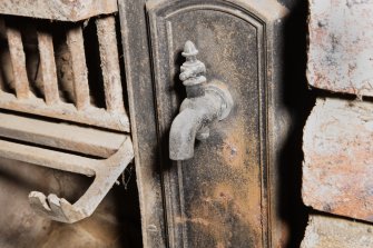 Interior. Detail of hot water tap on range within basement fireplace