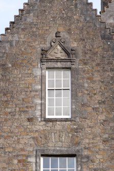 Detail of window with carved stone pediment on north gable of west facade