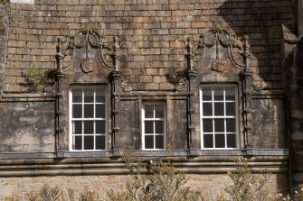 Detail of two dormer windows with carved stone pediments at 2nd floor level of west facade