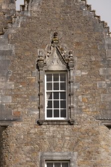 Detail of 2nd floor window with carved stone pediment on south gable of west facade