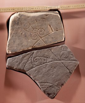 View of Pictish symbol stone fragment with replica fragment below (flash), including scale