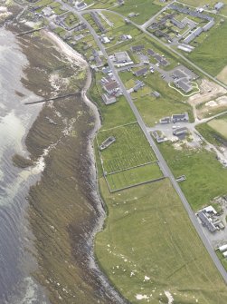 Oblique aerial view of Pierowall, centred on the cemetery and the Lady Kirk, looking SW.