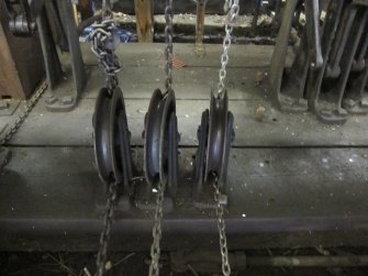 Interior. Locking Room, track side. Detail of pulley wheels guiding signal chain and wire, attached to lever and to signal bar above, which run under the walkway on south west side of signal box.