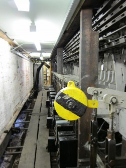 Interior. Locking Room. View along locking frame which sits below the bench (frame which guides the signal levers at first floor level), from south. Here we see a weighted lever painted black and yellow. These give extra purchase to levers which operate far flung signals. In this case, a signal 456 yards away from the signal box. The locking tray, levers and tails are visible.