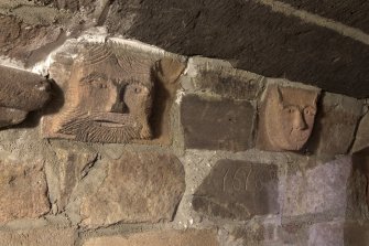 Ground floor. Corridor. Detail of carved heads and datestone.